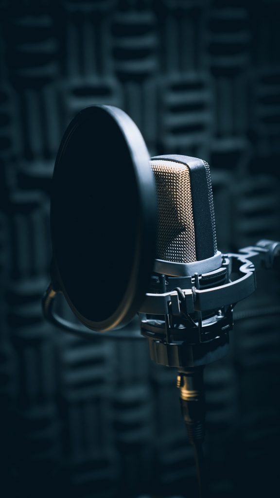 Programas RCN Close-up of a professional microphone with pop filter in a soundproof studio.